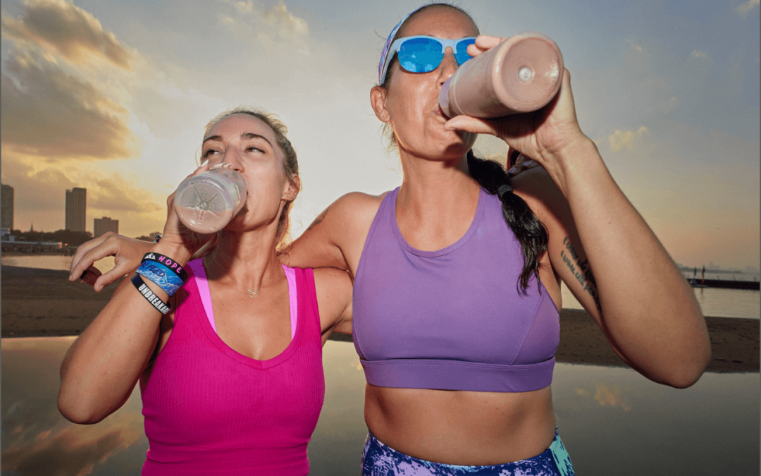 Two women drinking chocolate milk after a long run, in front of the Chicago River, during sunset.