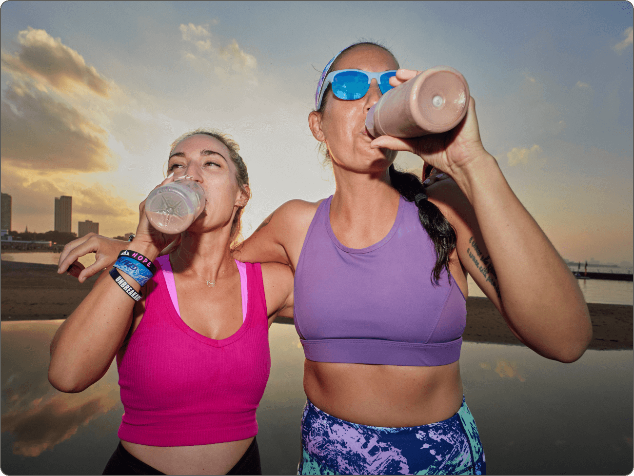 Two women drinking chocolate milk after a long run, in front of the Chicago River, during sunset.